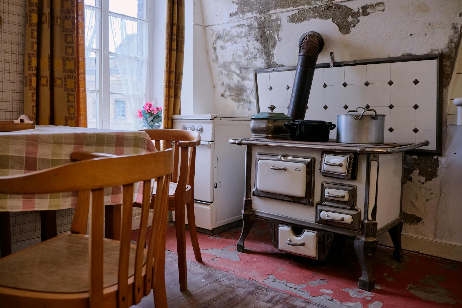 Przytulna stara kuchnia z rustykalnym piecem, drewnianymi krzesłami i obrusem w